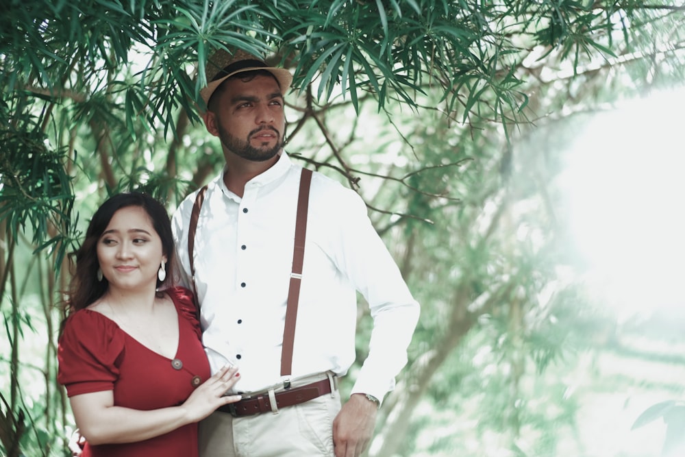 a man standing next to a woman under a tree