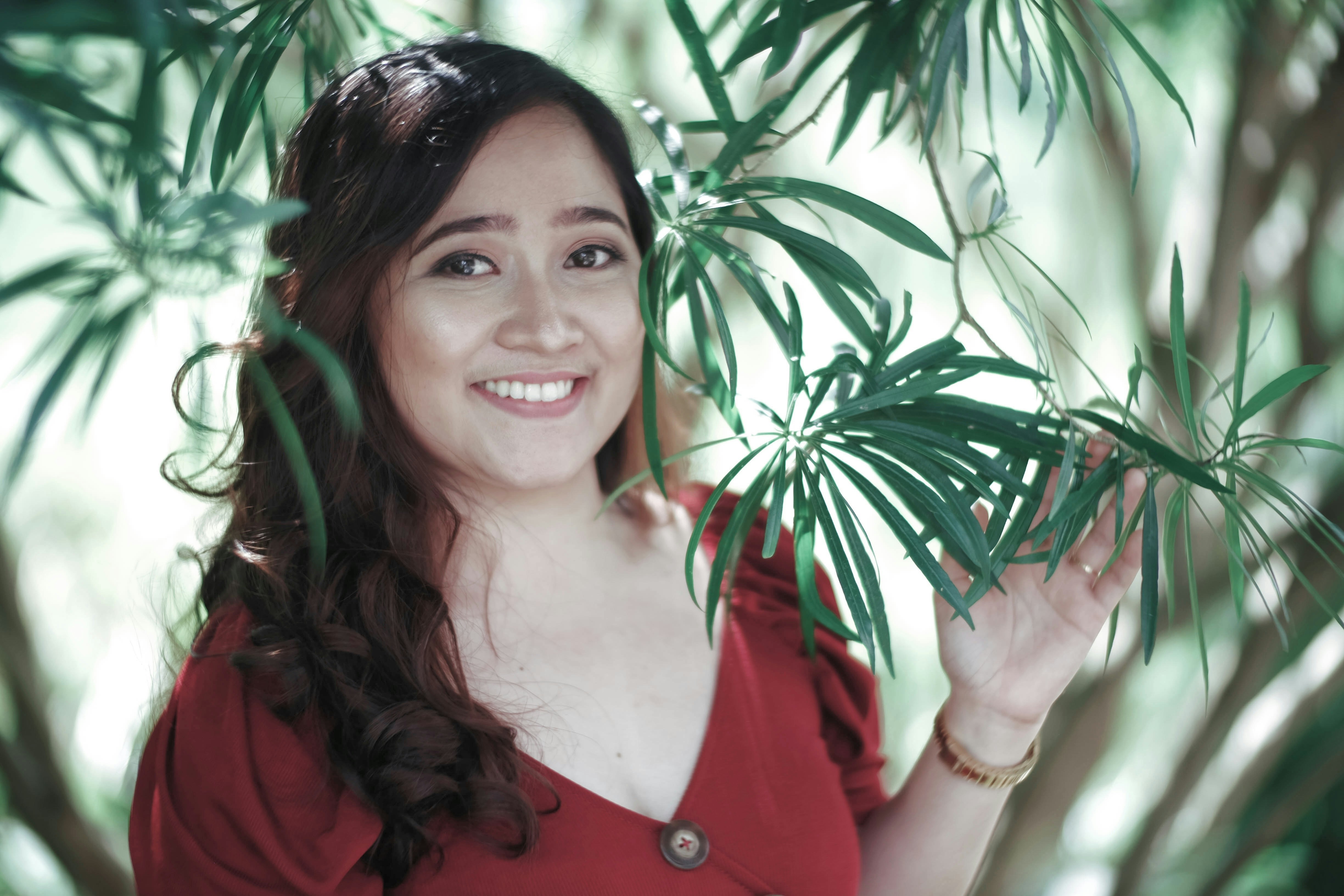 Una donna con una camicia rossa tiene in mano una pianta