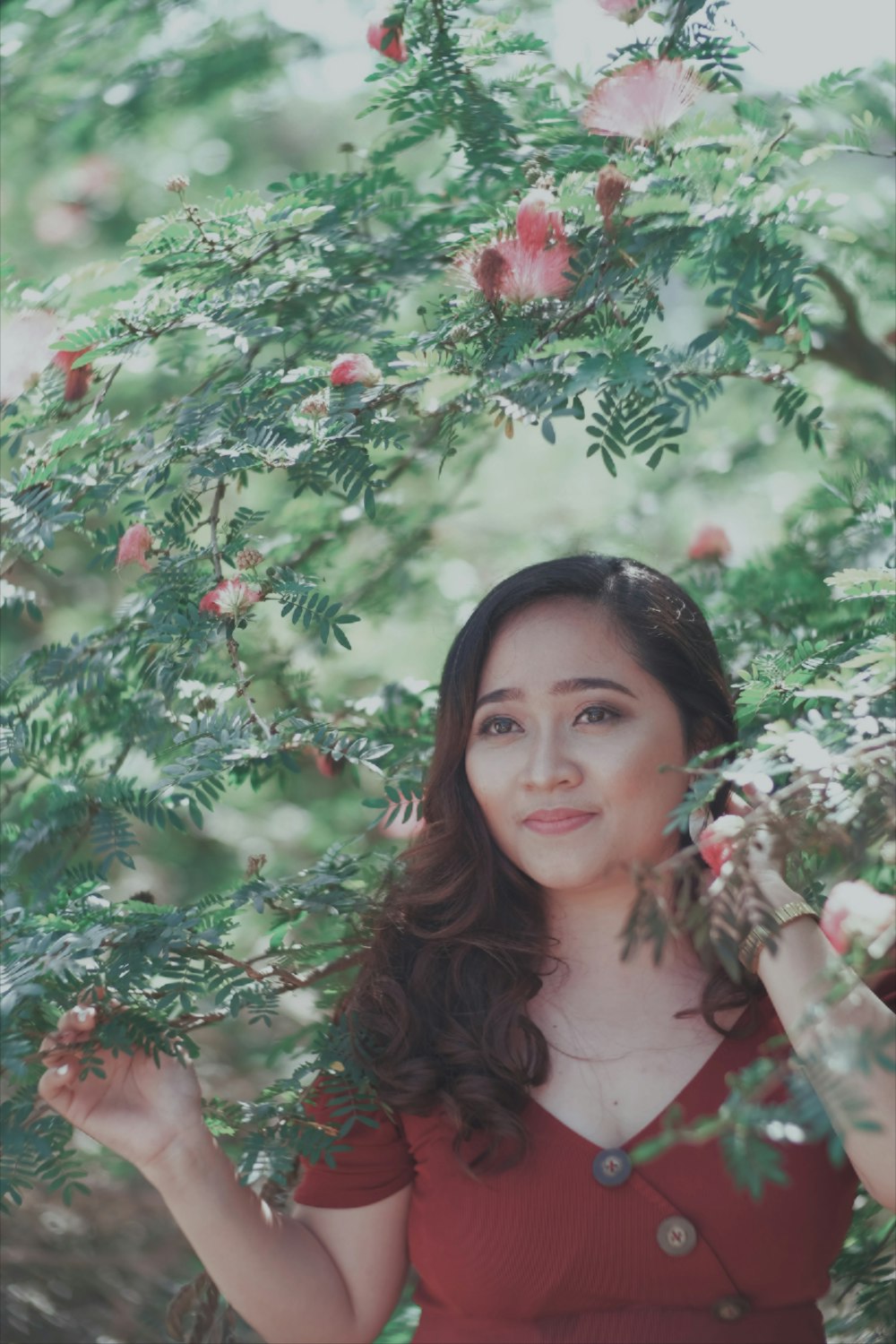 a woman in a red dress standing under a tree