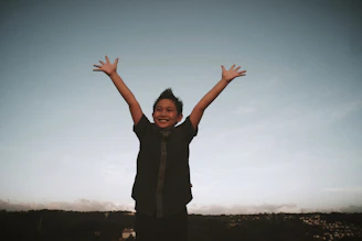 a young boy with his hands up in the air