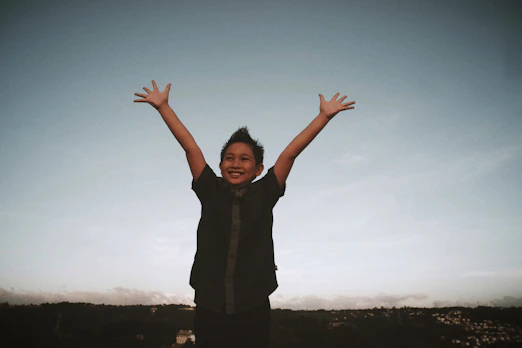 a young boy with his hands up in the air