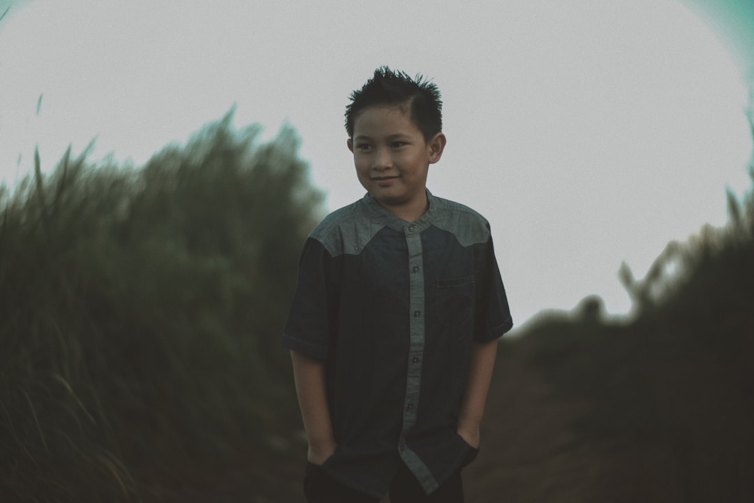 a young boy standing in a field of grass