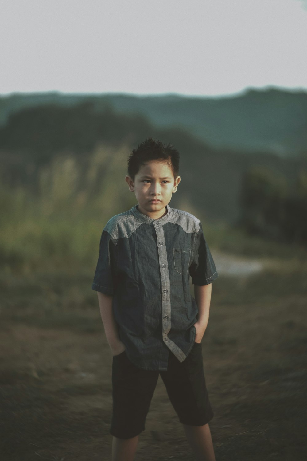 a young boy standing in a dirt field