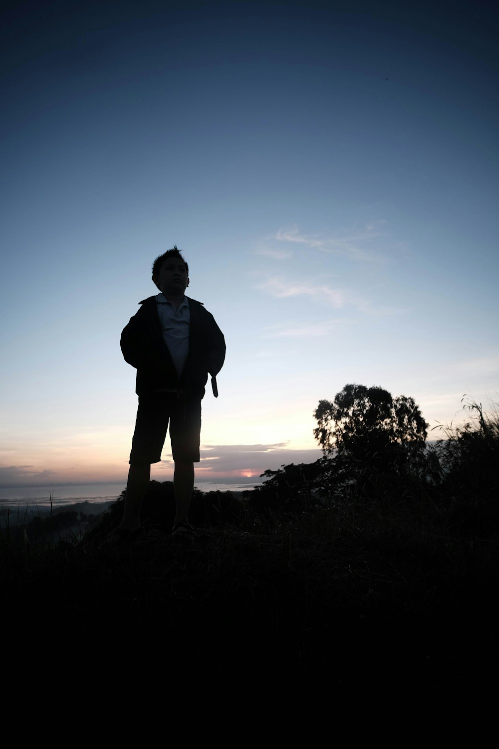 a man standing on top of a hill at sunset