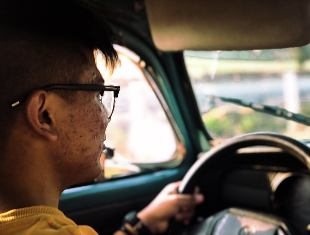 man in yellow shirt driving car