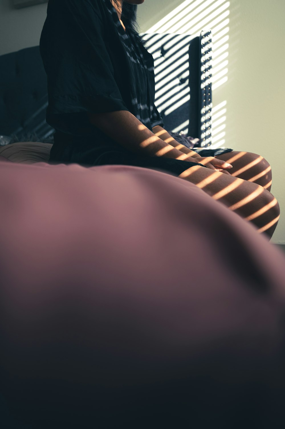 Person im schwarzen Hemd sitzt auf dem Bett