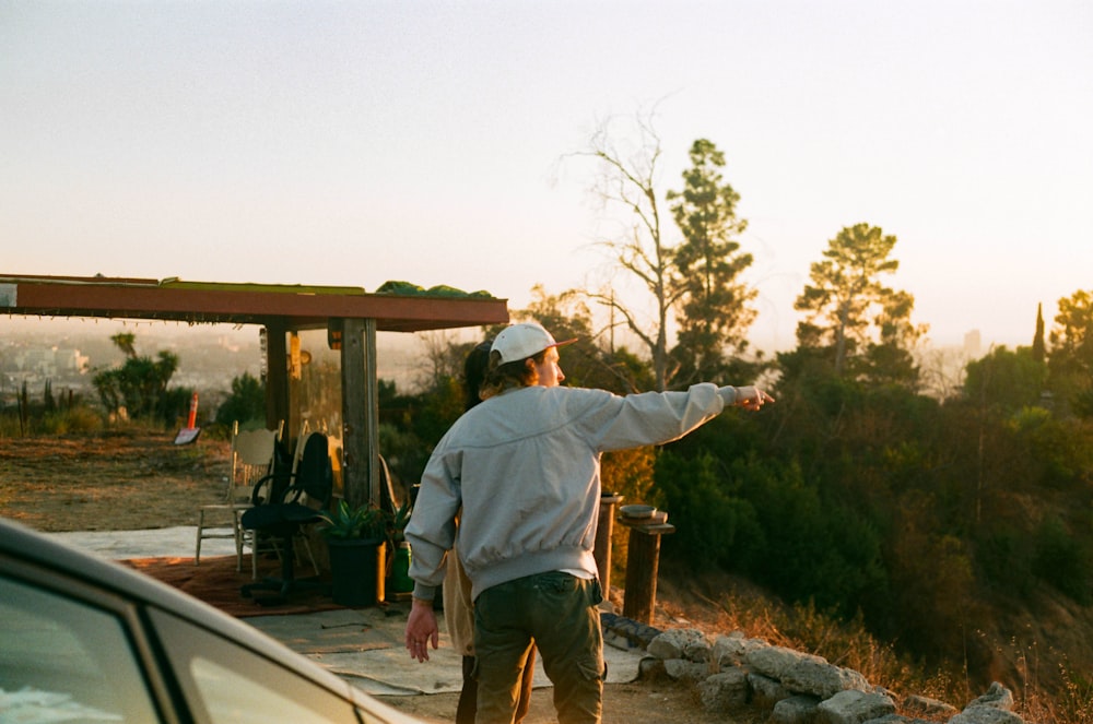 man in blue dress shirt and brown pants standing on gray rock during daytime