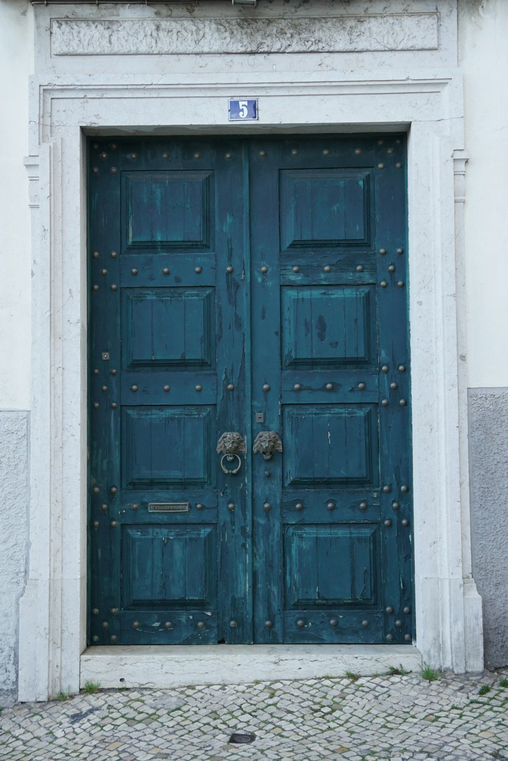 Puerta de madera azul sobre pared de hormigón blanco