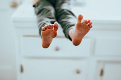 person in gray pants lying on white floor