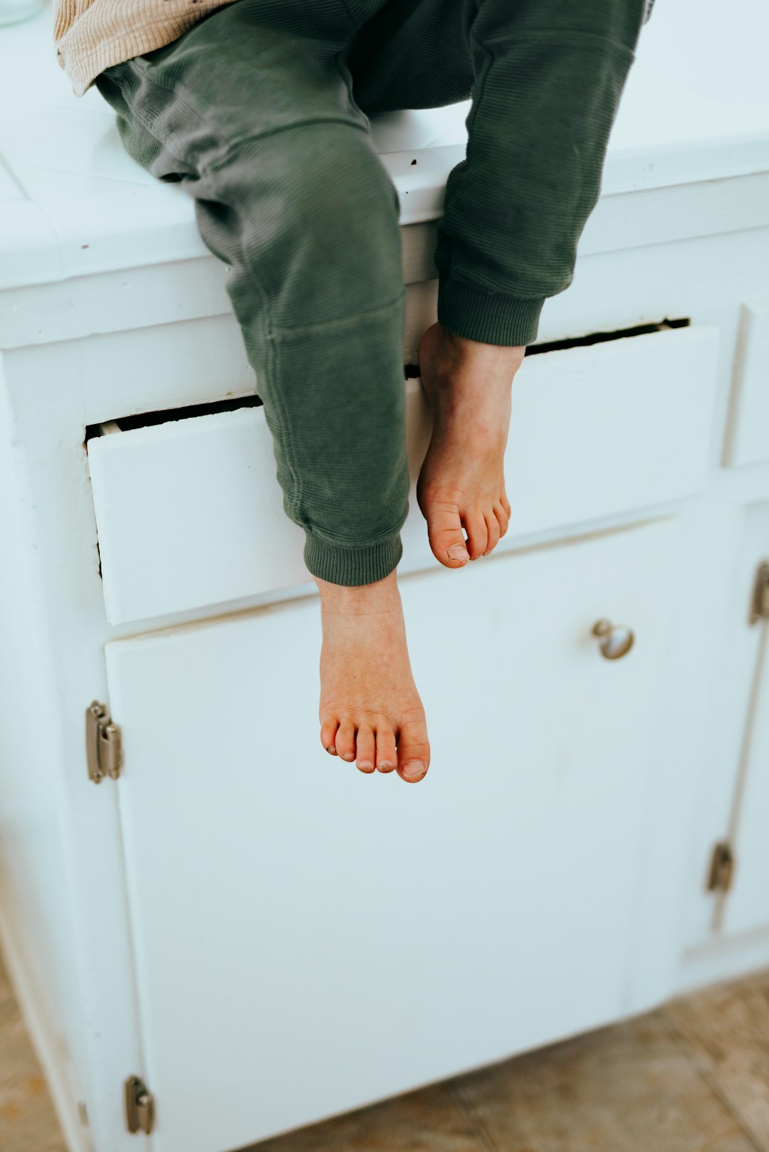 person in gray pants standing on white wooden cabinet