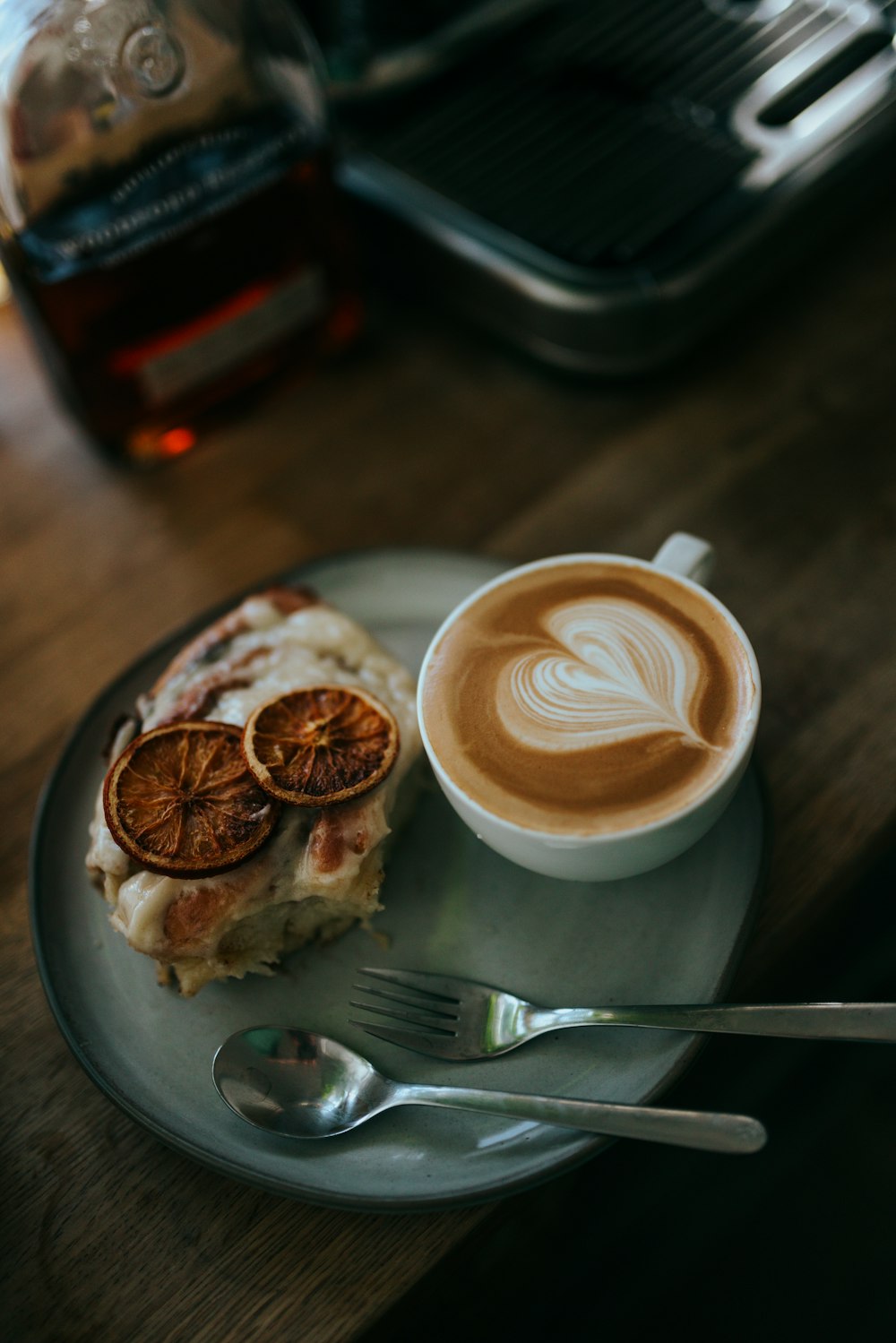 cappuccino in white ceramic cup on saucer beside stainless steel fork