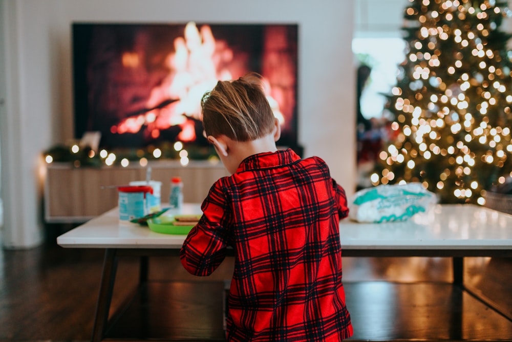 boy in red and black plaid dress shirt standing near table