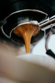 A barista pouring coffee into a glass, capturing the rich color and texture.