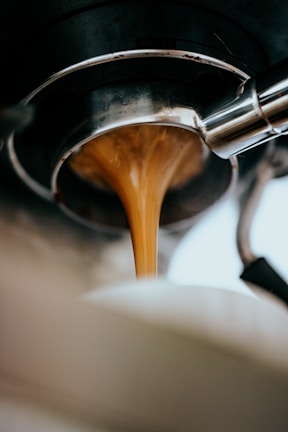 A barista pouring coffee into a glass, capturing the rich color and texture.