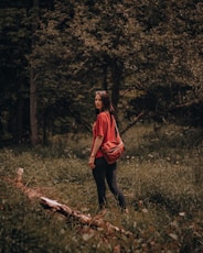 woman in red oversized sleeve shirt and black pants standing on brown log during daytime