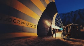 man in black shirt standing near blue and yellow hot air balloon during daytime