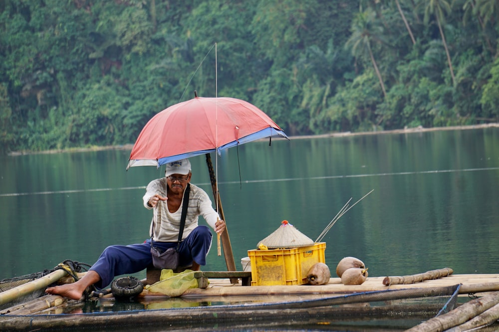 man in white jacket sitting on brown wooden bench near body of water during daytime