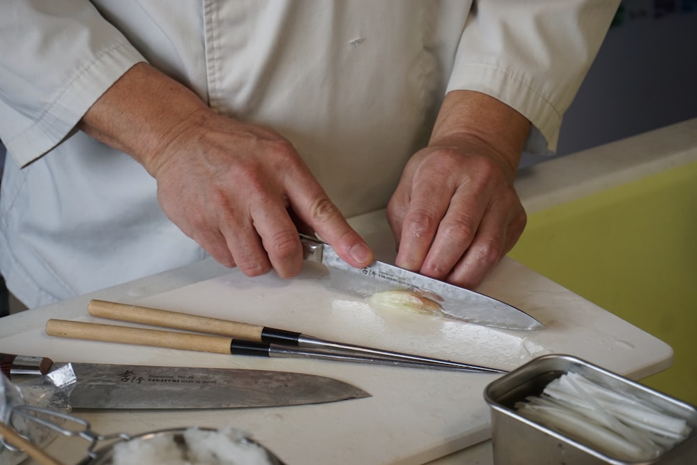 person in white button up shirt holding silver knife