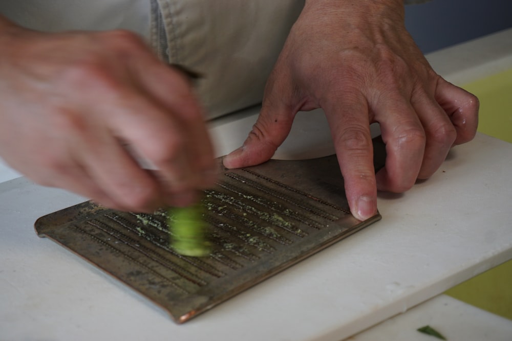 personne en chemise grise tenant une planche en bois verte et noire