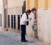 woman in white long sleeve shirt and black pants standing on sidewalk during daytime