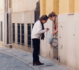woman in white long sleeve shirt and black pants standing on sidewalk during daytime