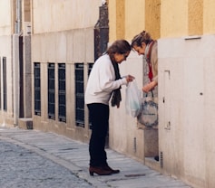 woman in white long sleeve shirt and black pants standing on sidewalk during daytime