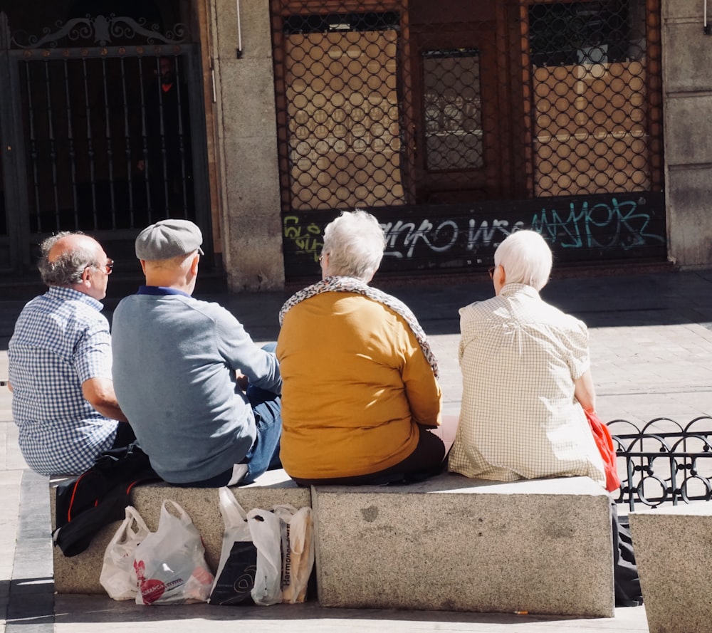 昼間に灰色のコンクリートのベンチに座る人々