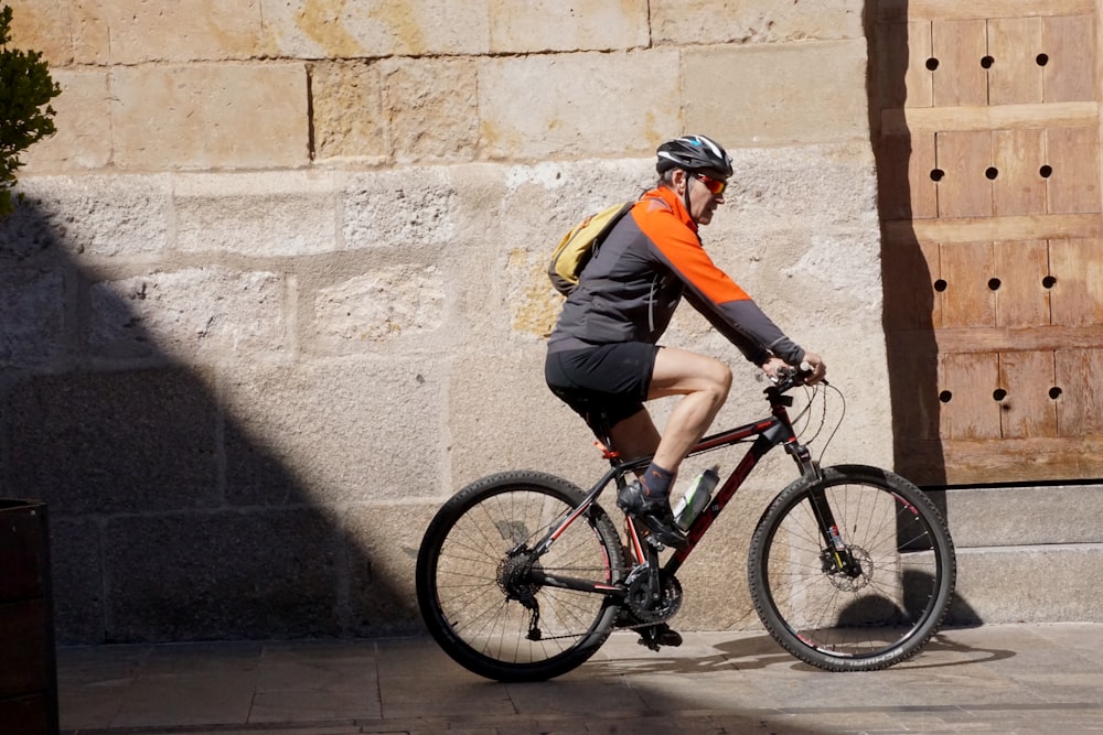 man in yellow and black jacket riding black and red bicycle