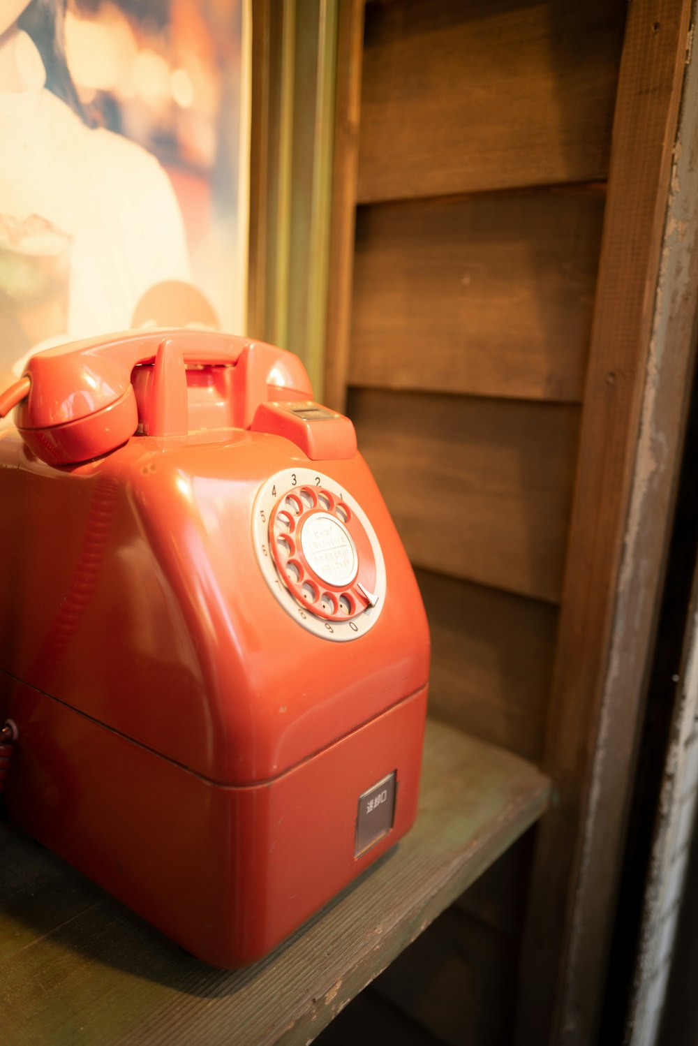 orange telephone on brown wooden shelf