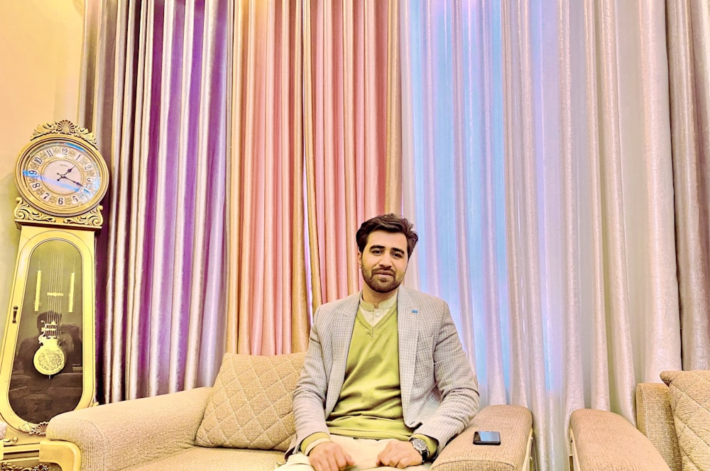 Mann in grauem Button-up-Langarmhemd sitzt auf braunem Sofa