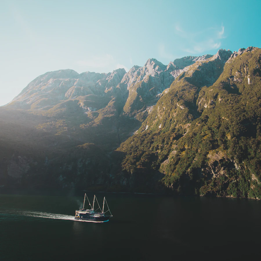 A boat crossing a fjord surrounded by mountains in New Zealand