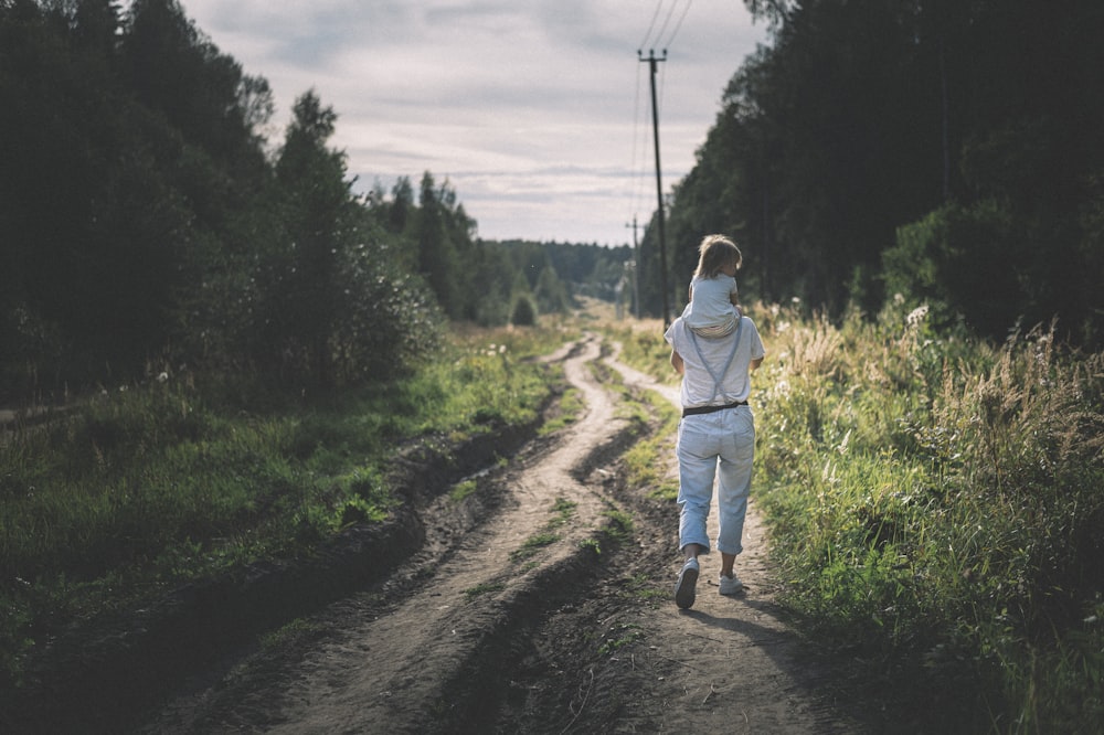 Mujer con chaqueta blanca caminando por un camino de tierra durante el día