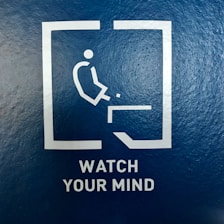 A minimalist pictogram of a person about to fall off an edge is enclosed in a square. Below the image, the words 'WATCH YOUR MIND' are printed in capital letters on a textured blue background.