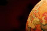 A close-up of a globe showing parts of Europe and Africa with names and borders visible. The focus is on the illuminated portion of the globe, highlighting colors and details against a dark background.