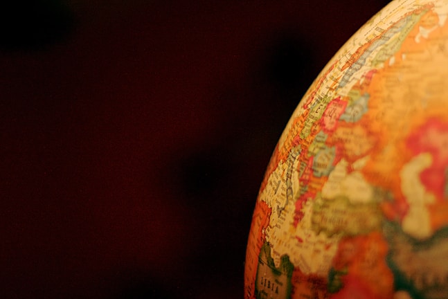 A close-up of a globe showing parts of Europe and Africa with names and borders visible. The focus is on the illuminated portion of the globe, highlighting colors and details against a dark background.