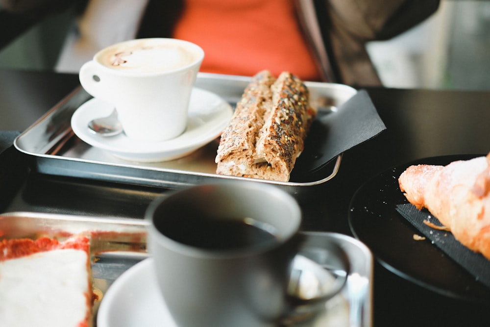 white ceramic teacup on saucer beside bread