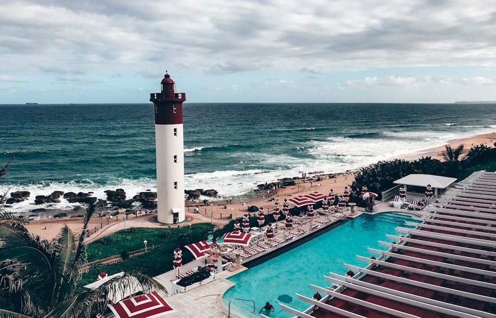 farol branco e vermelho perto do corpo de água durante o dia