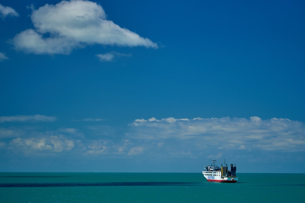 white and black ship on sea under blue sky and white clouds during daytime