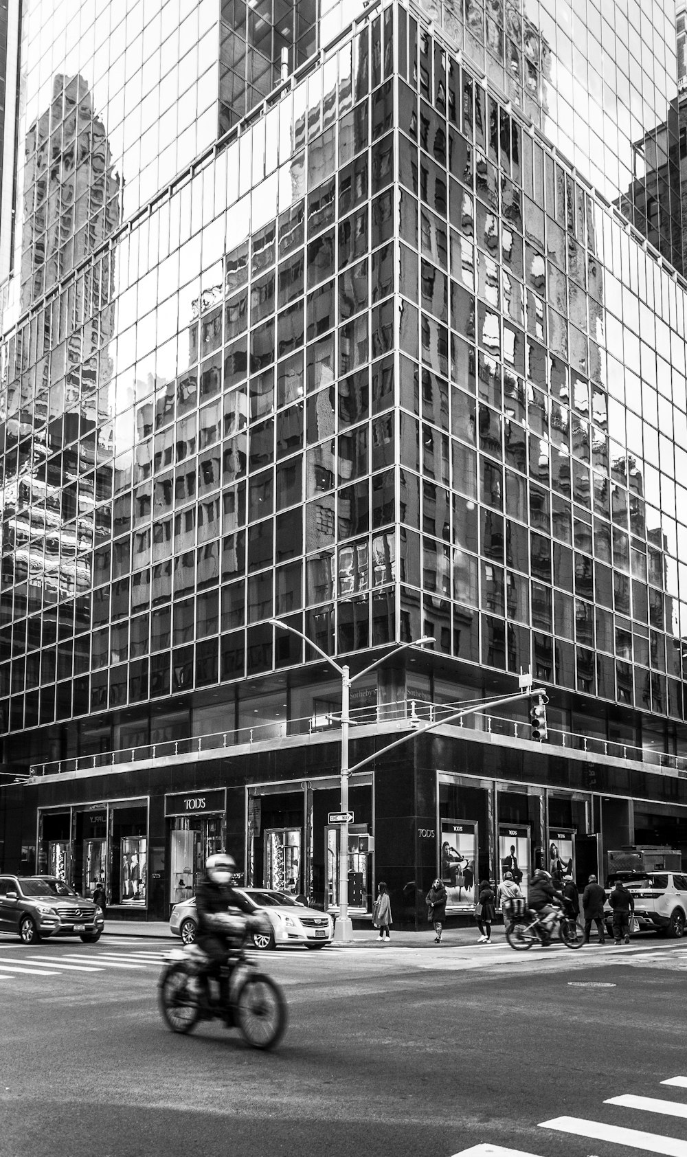 grayscale photo of people walking on street near high rise building