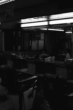 A sleek black-themed luxury barbershop interior with stylish chairs and elegant lighting