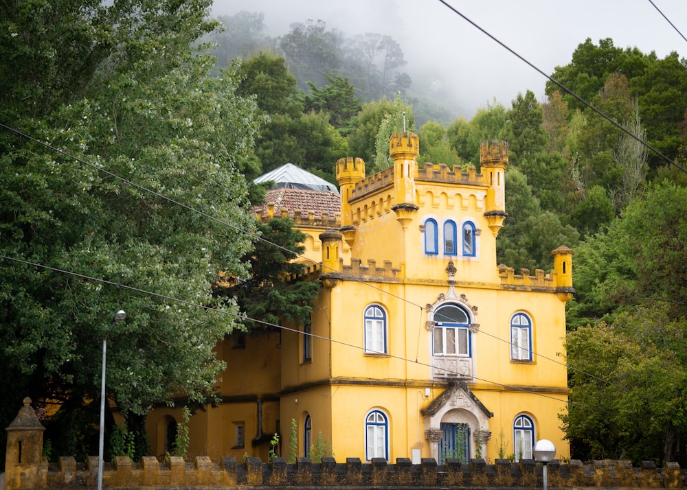 yellow and white concrete building near green trees under white clouds during daytime