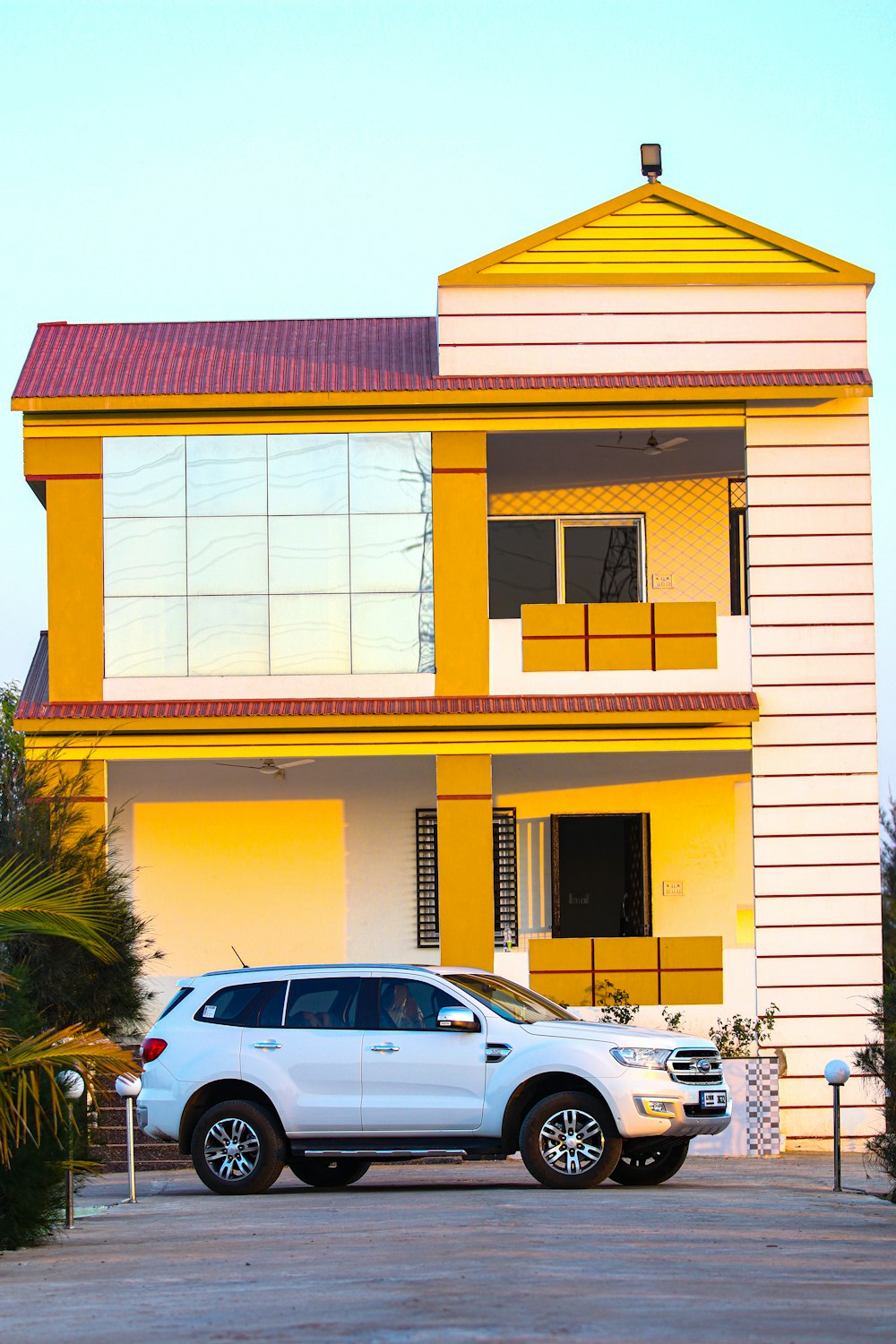white sedan parked beside white and yellow concrete building during daytime