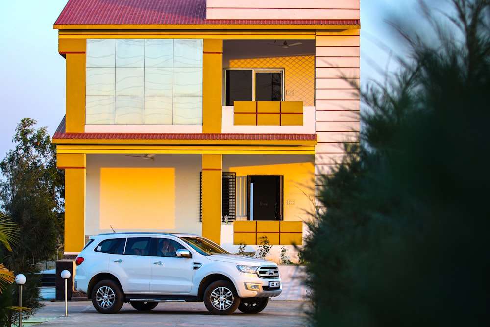 white sedan parked beside yellow and pink concrete building