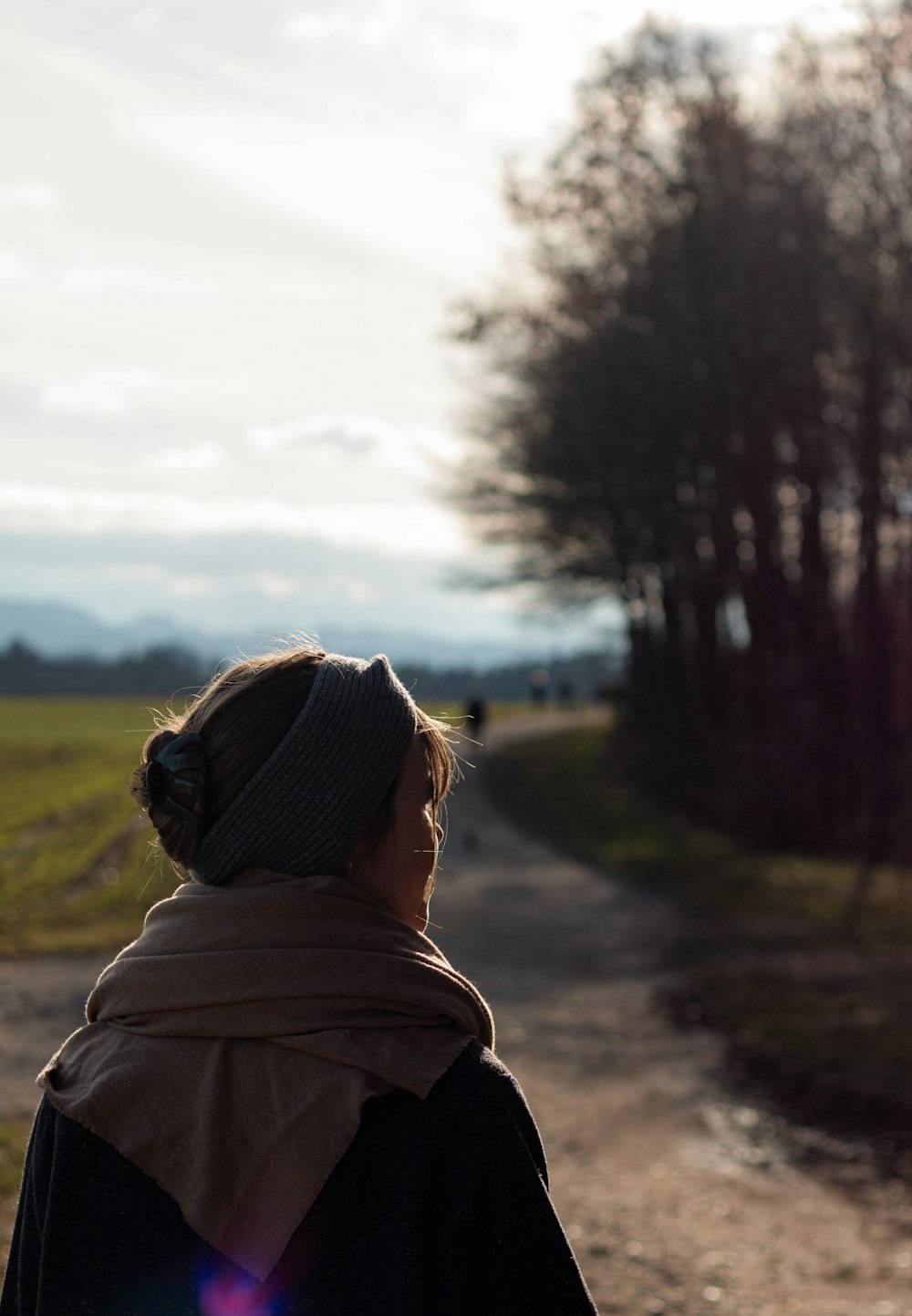 Femme en sweat à capuche marron debout sur un chemin de terre pendant la journée