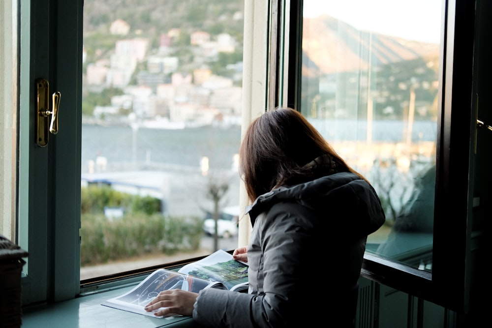 woman in black jacket sitting by the window