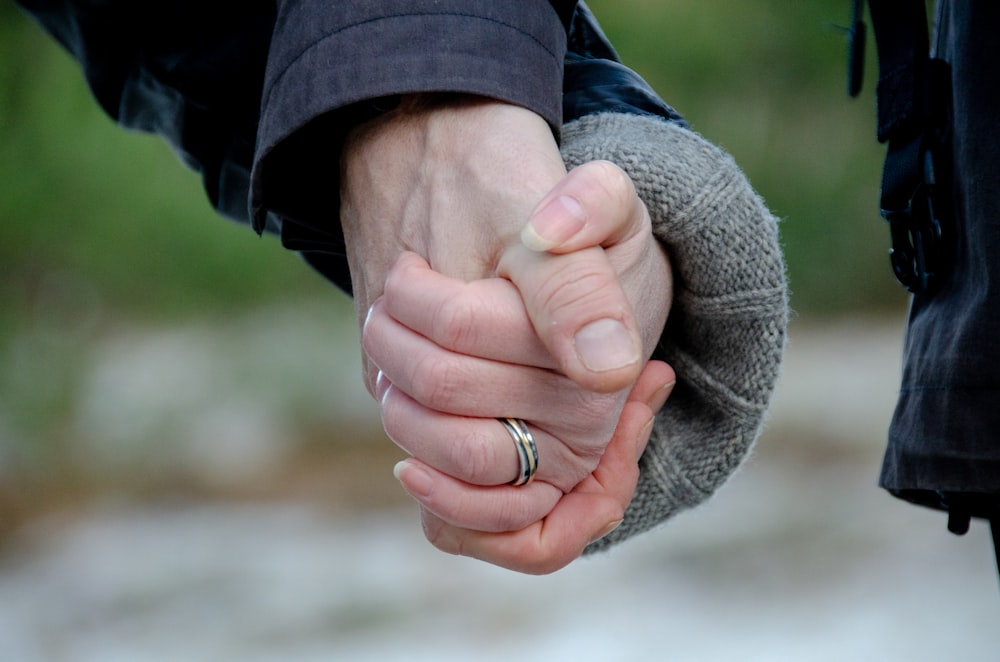 person in blue jacket holding womans hand