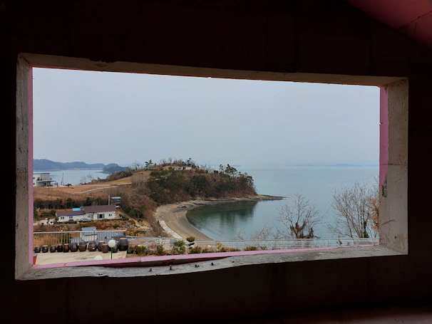 A friendly technician cleaning a large window with a scenic Santa Cruz beach view in the background.