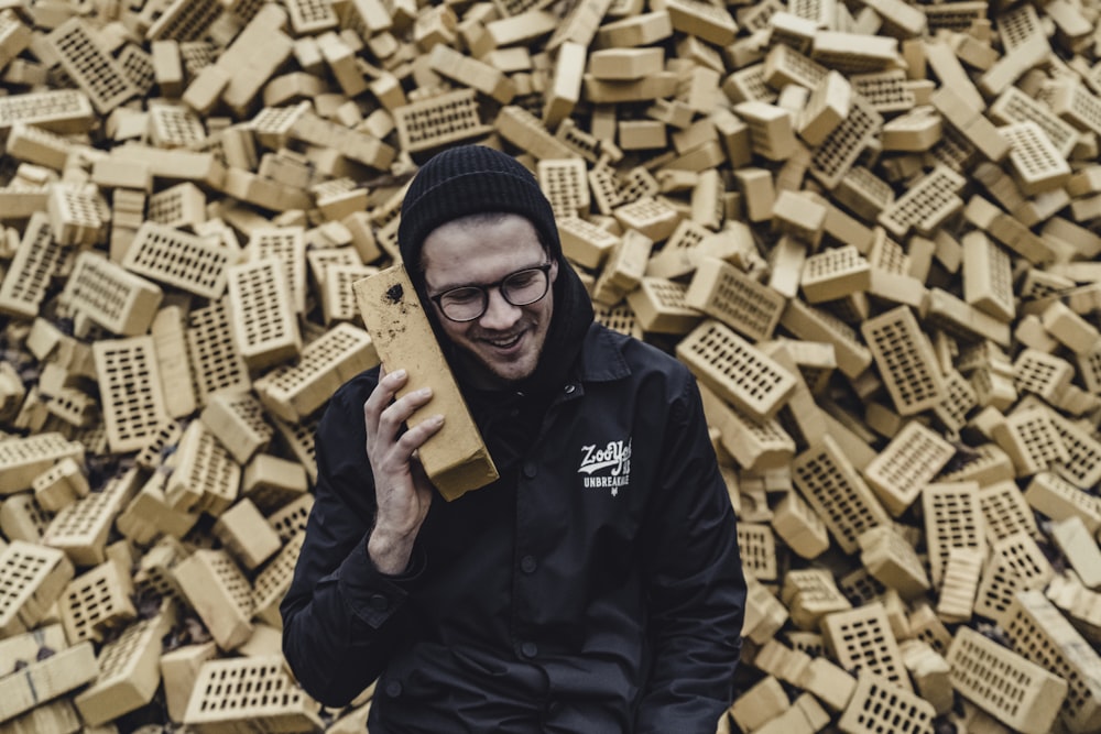man in black jacket holding brown wooden blocks