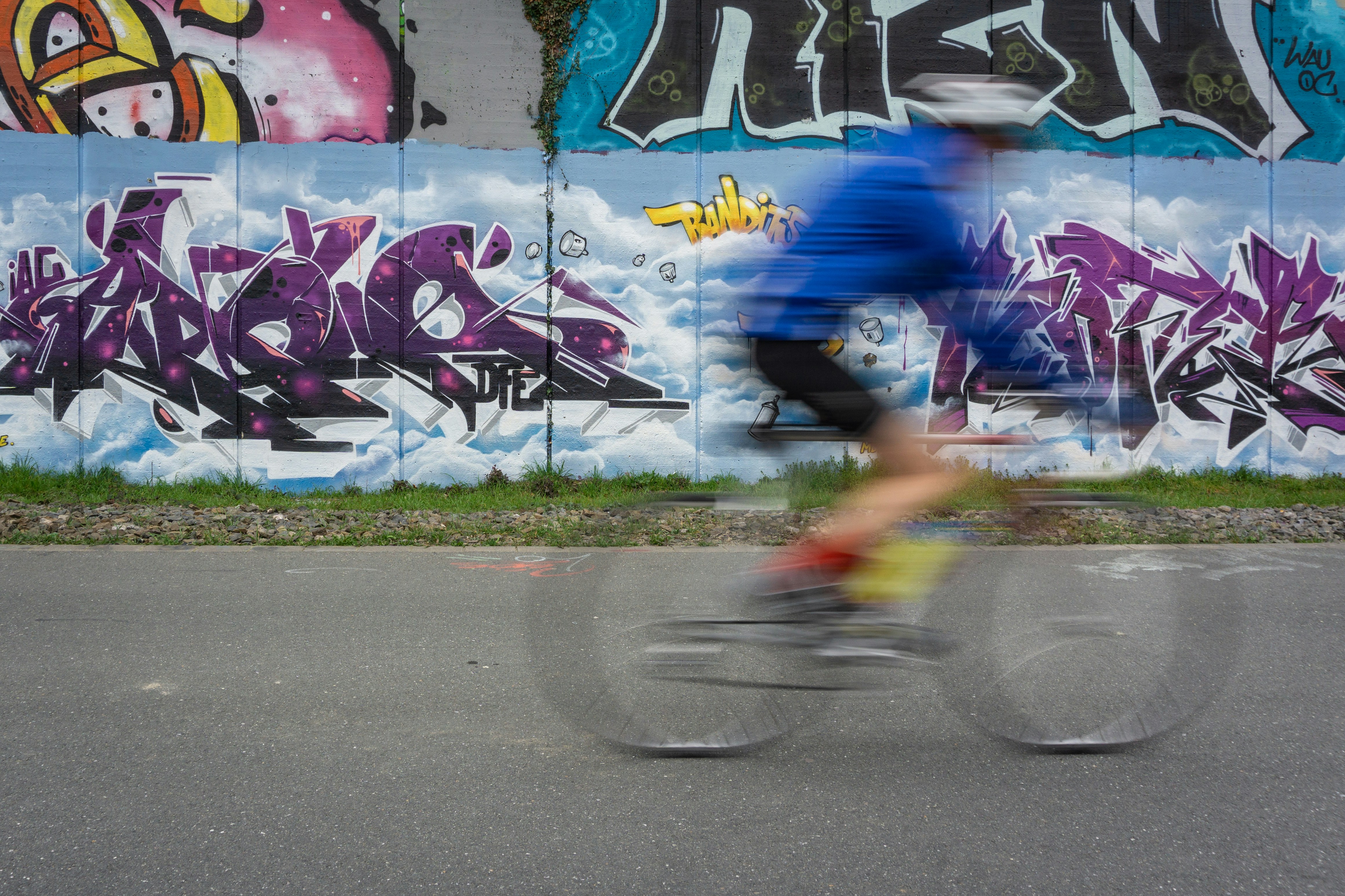girl in blue shirt and pink shorts riding bicycle on road during daytime