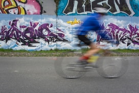 girl in blue shirt and pink shorts riding bicycle on road during daytime